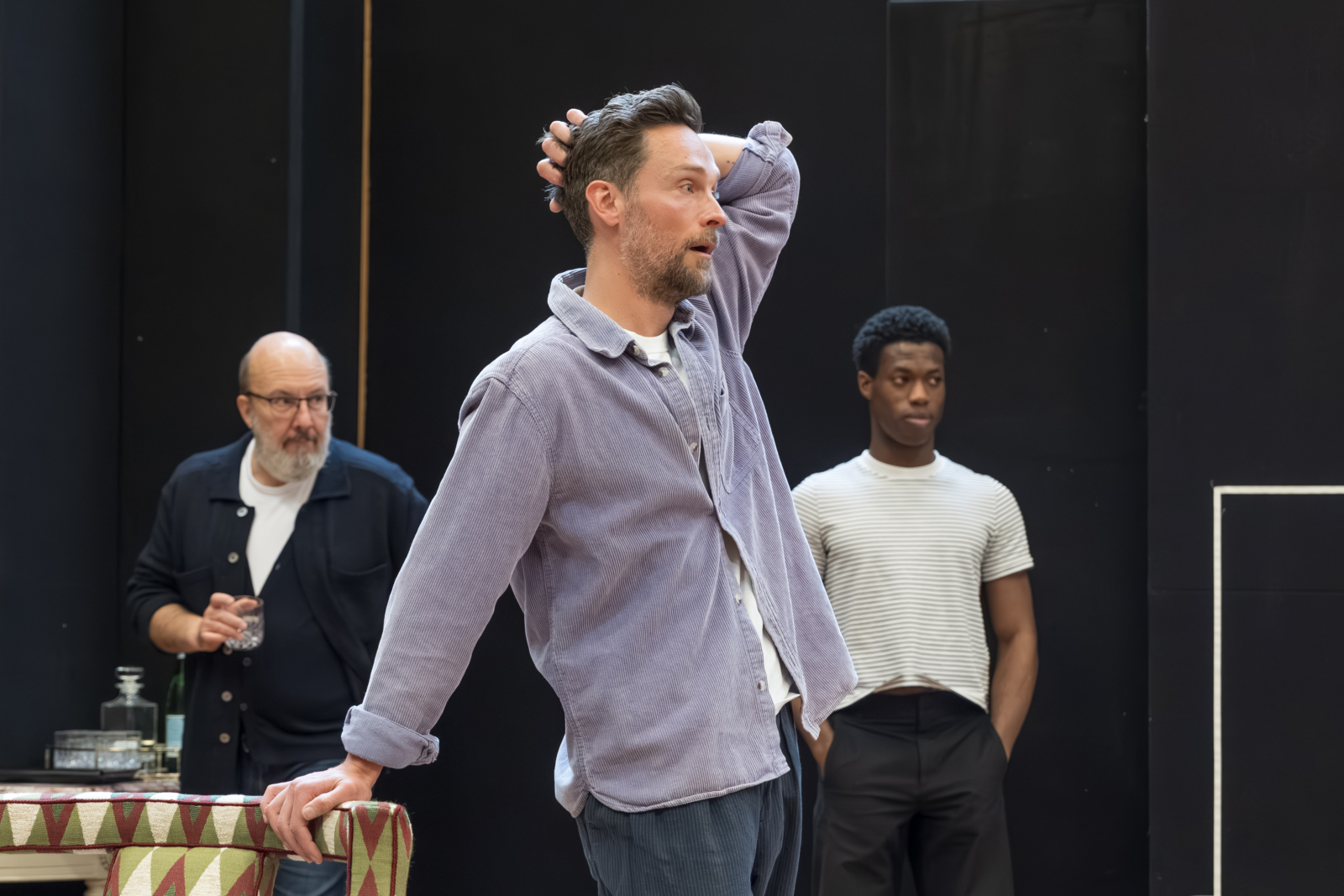 Rehearsal photo shows Tom in a denim shirt with his hand on his head